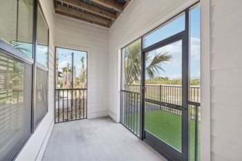 A balcony with a black railing and glass doors overlooking a green lawn.
